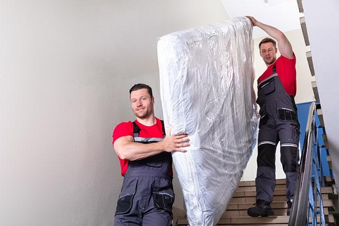 two people carrying a box spring down a staircase in Silver Grove, KY